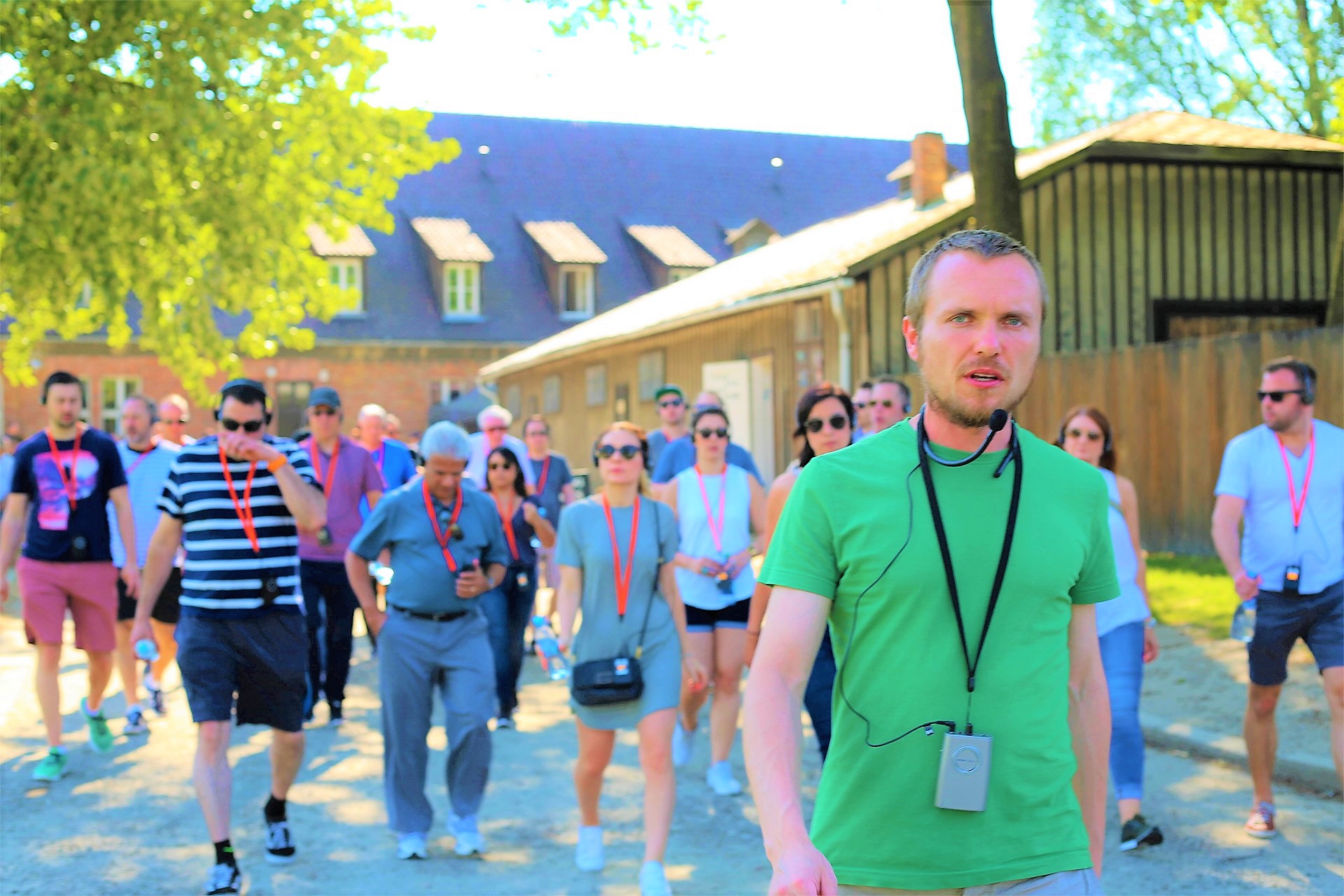 Grupa zwiedzająca Auschwitz z edukatorem i zestawami audio
