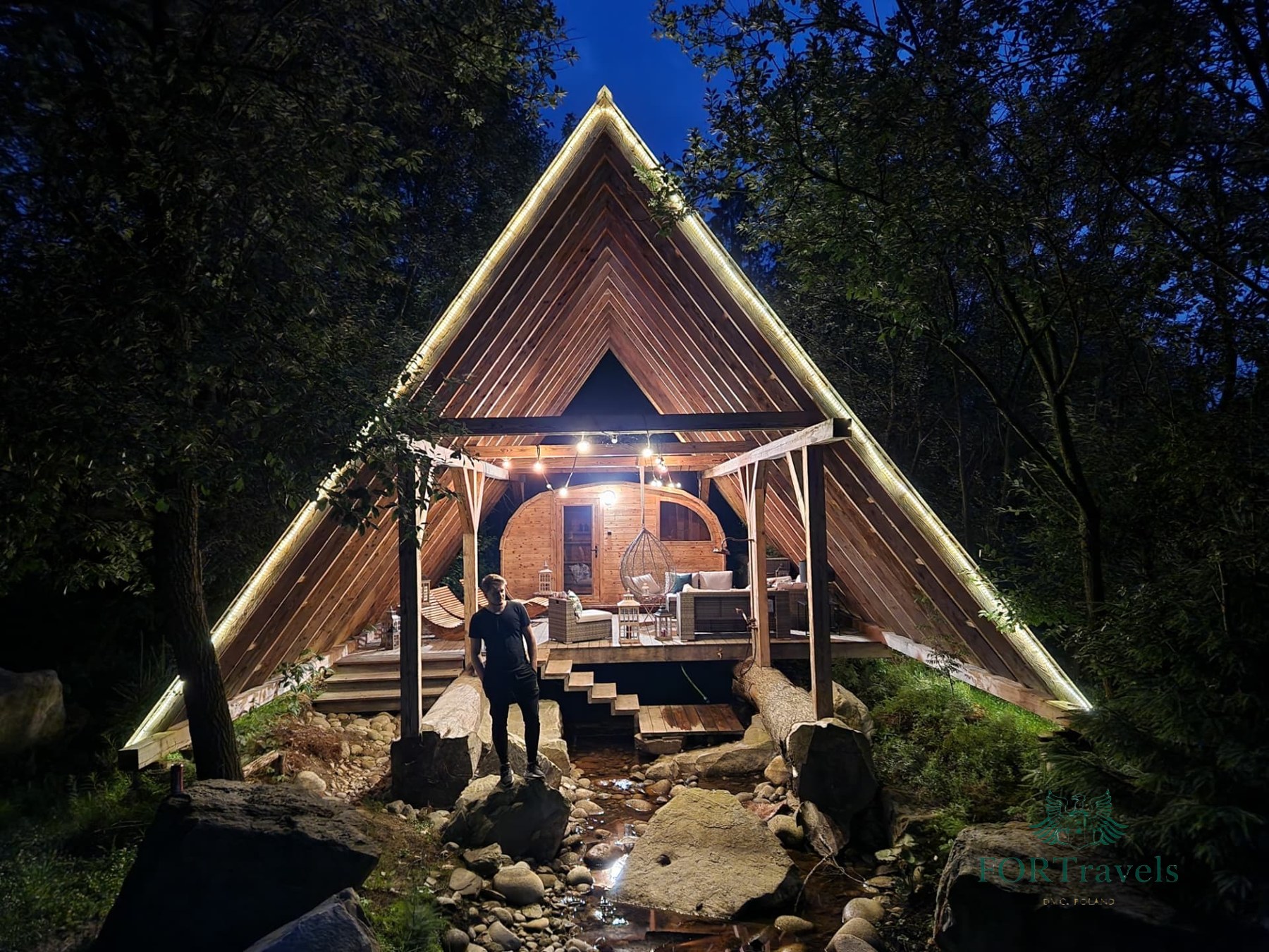 Podświetlony domek glampingowy nad potokiem wieczorem – FORTravels DMC Poland